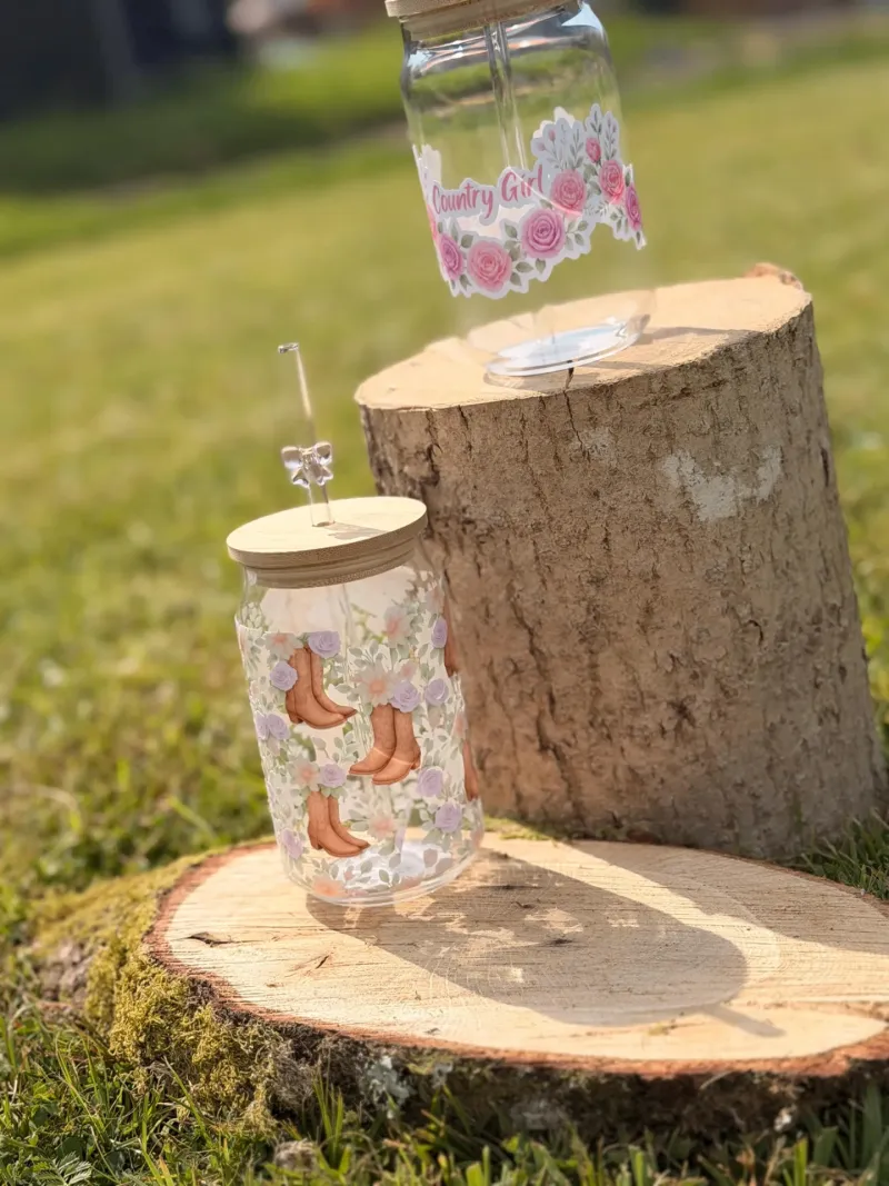 Floral cowgirl glass tumbler with a bamboo lid and glass straw on a wooden table