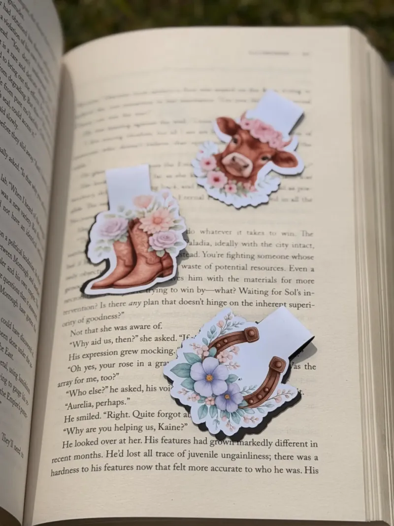 Three countryside-themed magnetic bookmarks resting on an open book